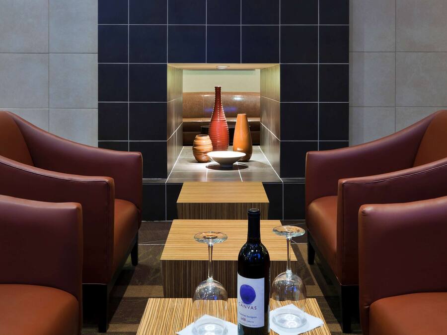 Un espace détente moderne avec des canapés en cuir, une table basse en bois et une bouteille de vin.
