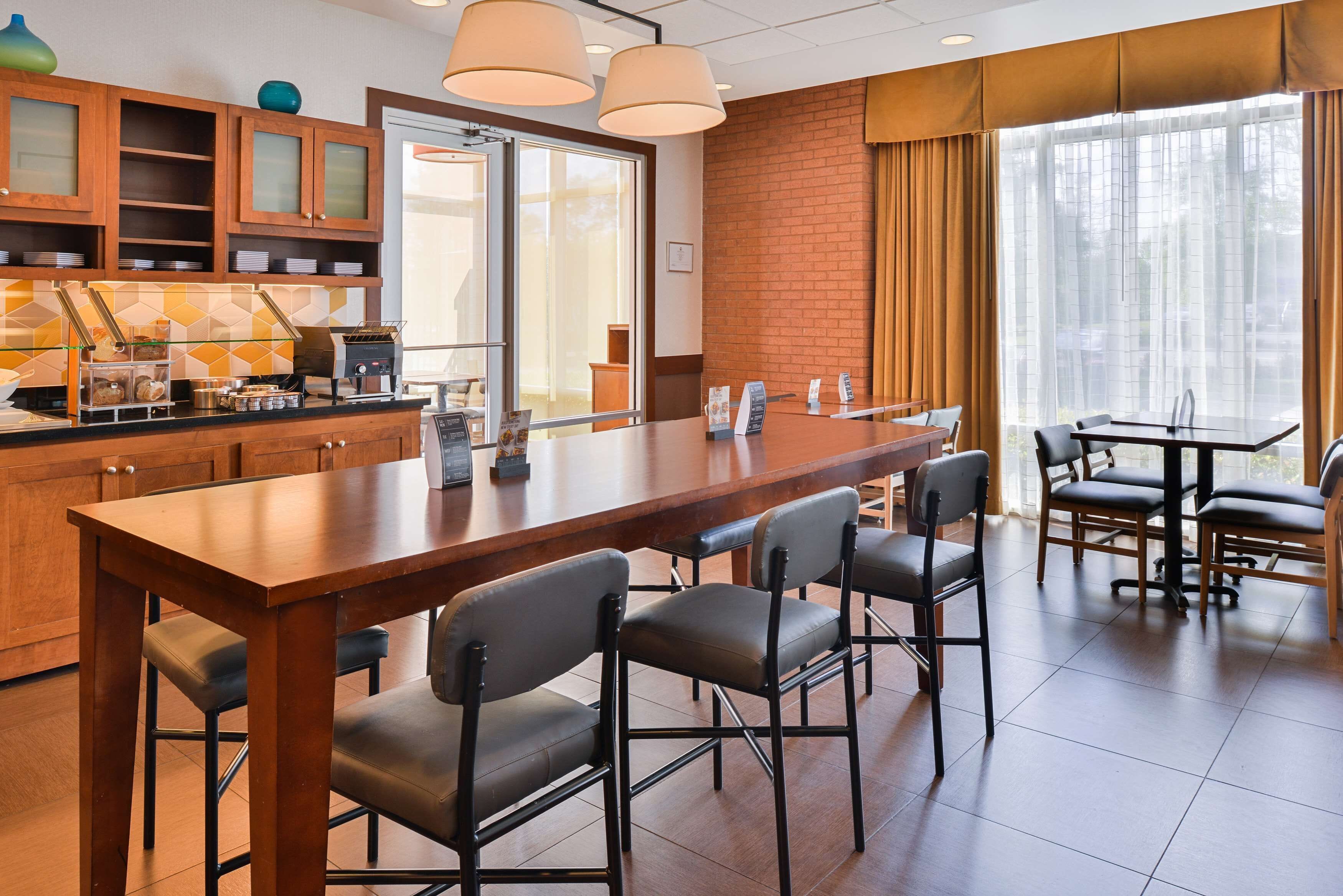 Eine moderne Hotelküche mit einer langen Theke, Barhocker und einem Essbereich mit Tisch und Stühlen.