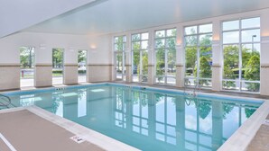 An indoor swimming pool with clear windows, a ladder, and a lifeguard chair.