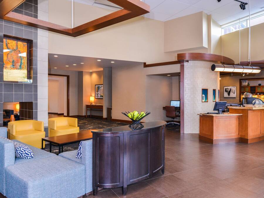 A lobby with a reception desk, seating area, and a fireplace.