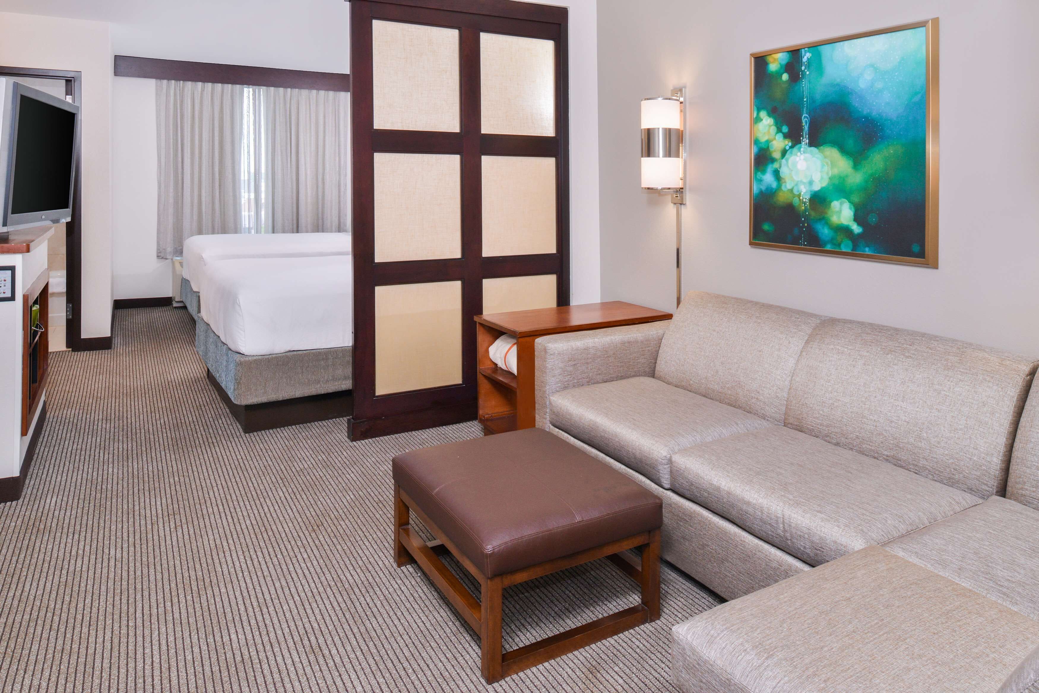 Une chambre d’hôtel avec un lit, un canapé, une petite table, une télévision et un tableau au mur.