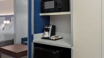 A compact kitchenette with a microwave, coffee machine, and a small refrigerator.