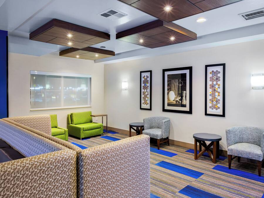 A hotel lobby with seating areas, framed artwork on the walls, and a large window providing a view.