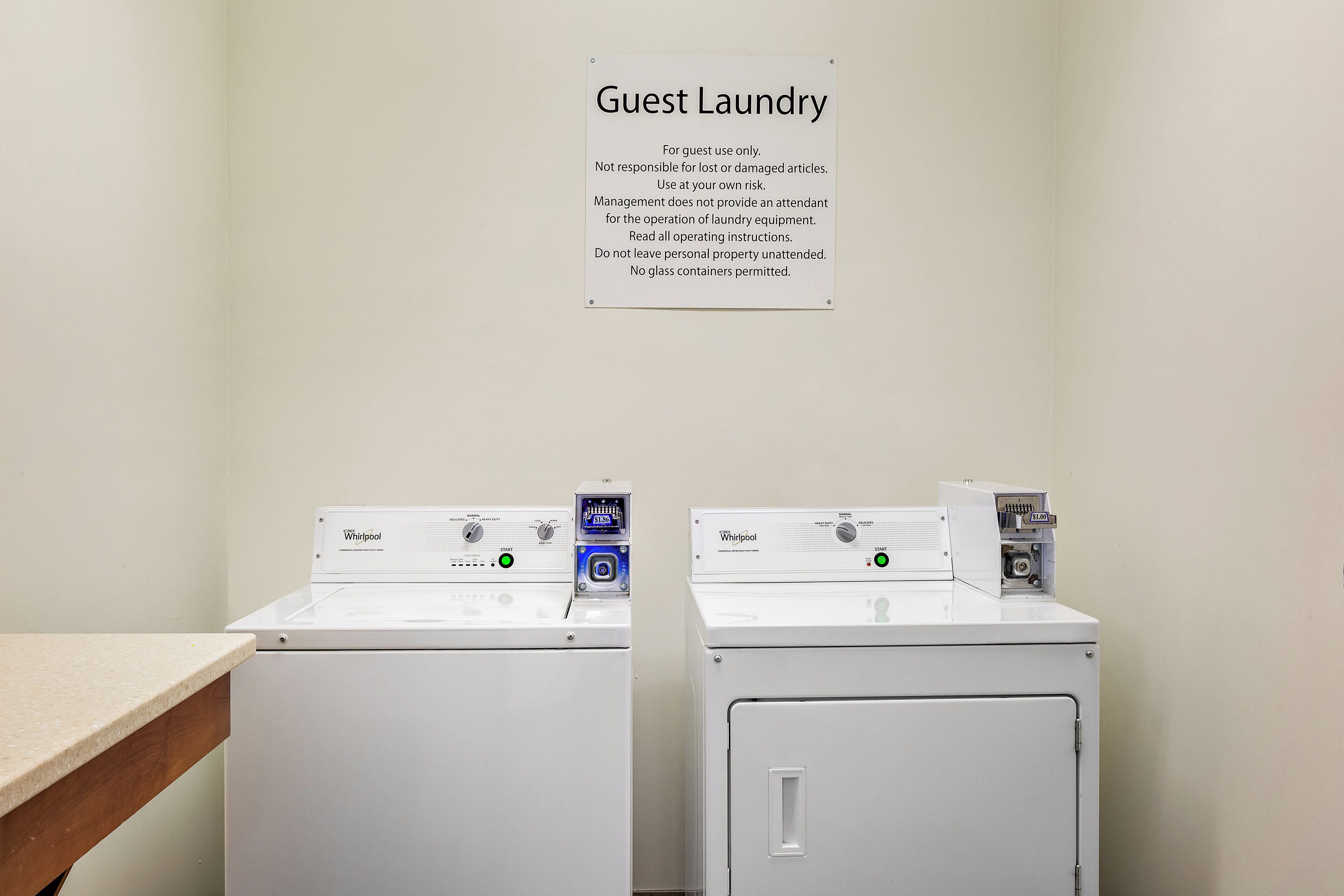 A guest laundry area with two Whirlpool washing machines and a sign with usage instructions.