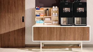 A kitchenette with a coffee machine, a kettle, and storage shelves.
