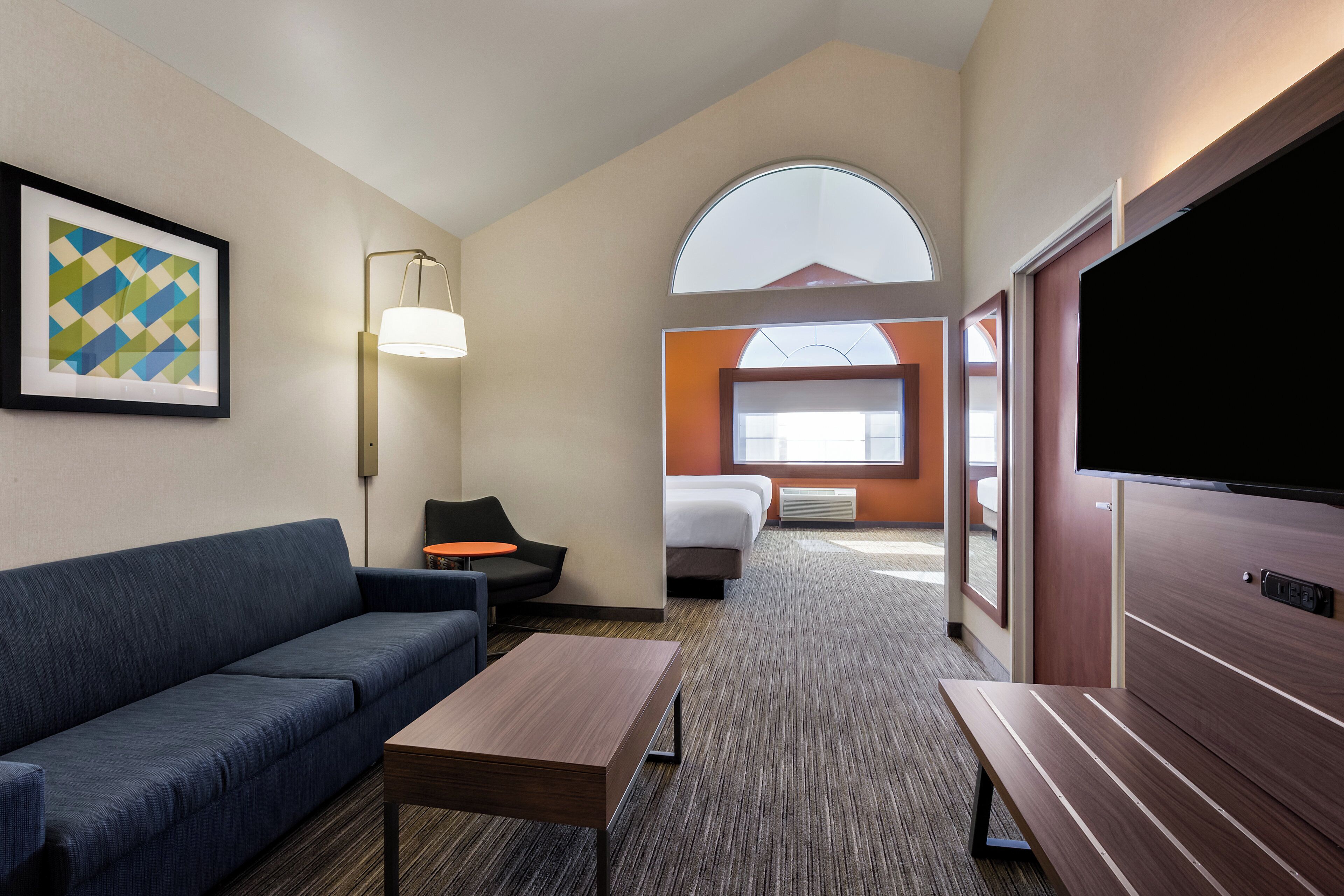 Een hotelkamer met een bank, een eettafeltje, een televisie, een bed en een raam met uitzicht.