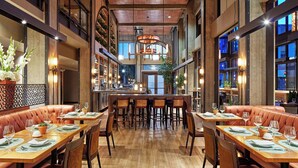 A spacious restaurant with high ceilings, exposed beams, and a central bar area.