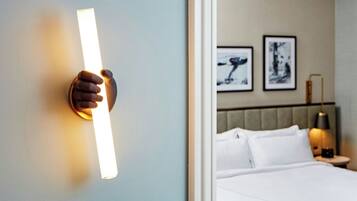 A hotel room with a bed, a nightstand, and wall-mounted artwork.
