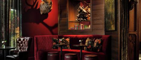 A cozy room with a red upholstered sofa, a wooden bookshelf, and a mounted deer head.