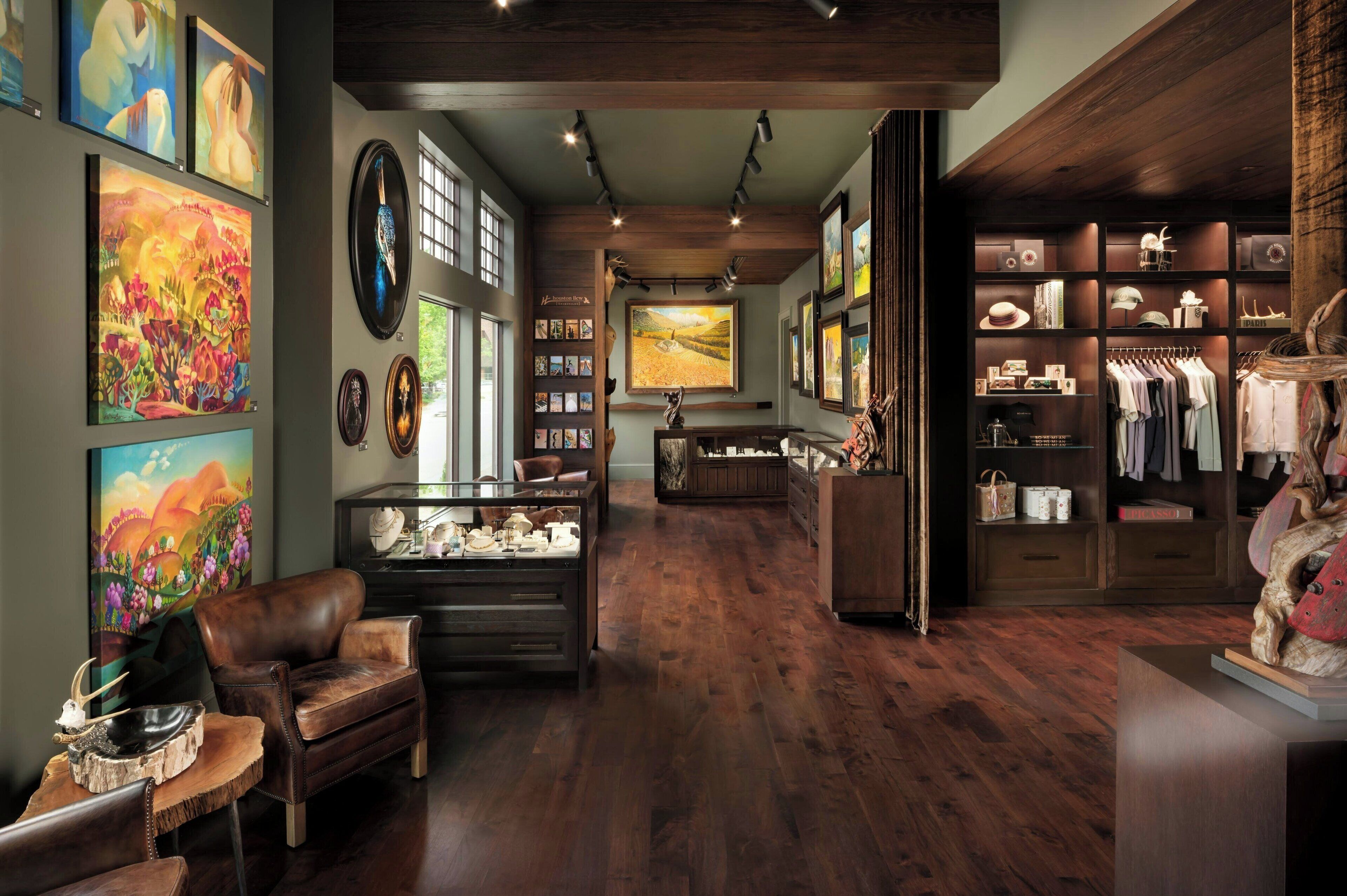 A spacious room with a wooden floor, a leather armchair, a glass display case, and a clothing rack.