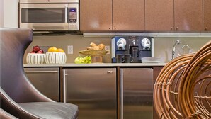 A modern kitchen with stainless steel appliances, a dining area with a leather chair, and a unique woven chair. - The Inn At St Botolph (Boston)