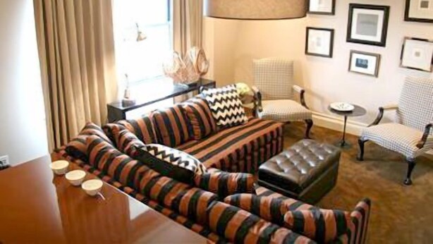A living room with a sofa, ottoman, and chairs, a coffee table, and a lamp. - The Inn At St Botolph (Boston)