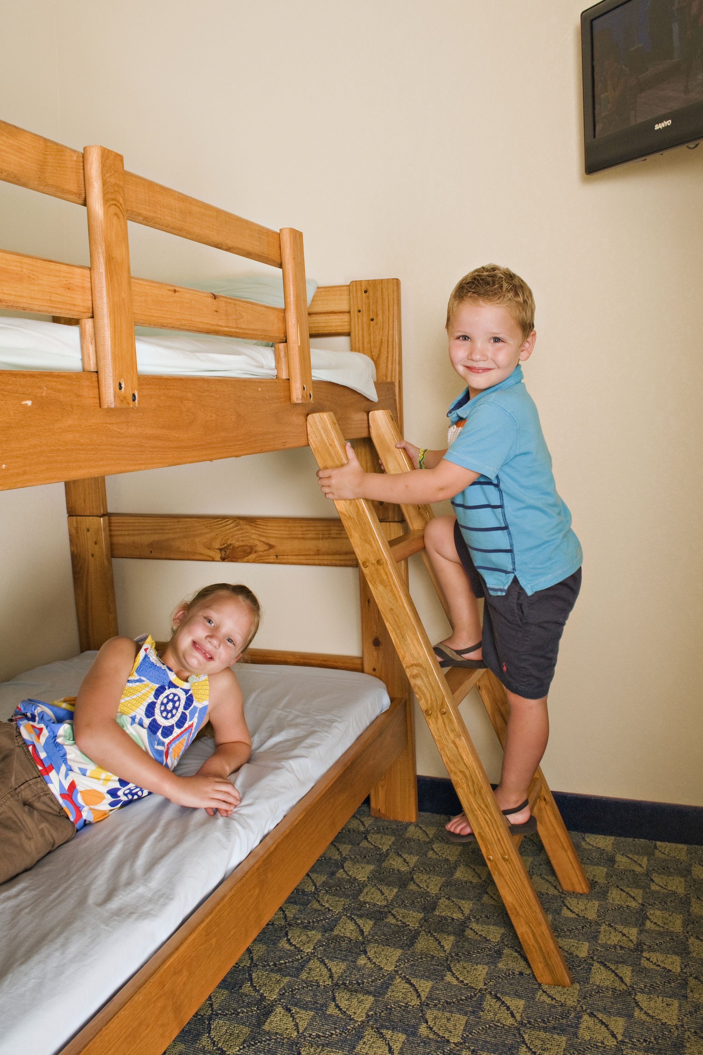 A bunk bed with two children climbing the ladder.