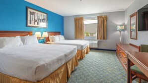 Habitación de hotel con dos camas, un aparador, un escritorio, una lámpara, una ventana con cortinas y un cuadro en la pared.