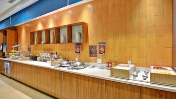 A buffet counter with various food items and condiments, wooden paneling, and a blue ceiling.
