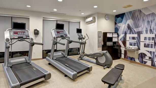 A gym with treadmills, an elliptical, and a bench.