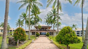 A pathway leading to a building surrounded by palm trees and well-maintained greenery. - Nirwana Beach Club (Bintan)