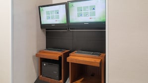 Twee monitoren bevestigd aan een muur, elk met een toetsenbord en een printerlade eronder.
