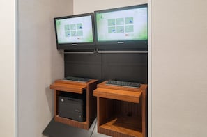 Twee monitoren bevestigd aan een muur, elk met een toetsenbord en een printerlade eronder.
