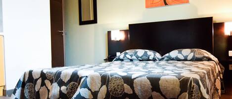 Ein Hotelzimmer mit Bett, Nachttisch, Wandspiegel und einem Gemälde.