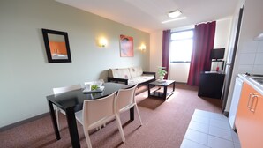A compact living space with a dining area, kitchenette, and a sofa. - Residhotel Lyon Lamartine (Tassin-la-Demi-Lune)