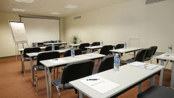 A conference room with multiple tables, chairs, and a projector screen.