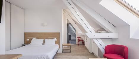 Una habitación de hotel moderna con cama, escritorio, silla y tragaluz.