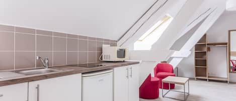 A modern kitchen with a built-in microwave, white cabinets, and a wooden countertop.