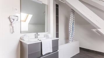 Een moderne badkamer met een grote spiegel, een witte wastafel en een haardroger bevestigd aan de muur.