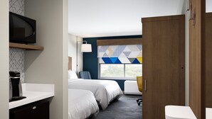 Une chambre d’hôtel équipée d’un lit, d’une chaise, d’un bureau, d’une machine à café et d’une télévision.