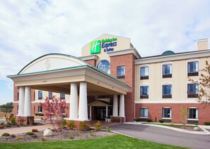 A Holiday Inn Express & Suites with a covered entrance, brick facade, and a clear sky.