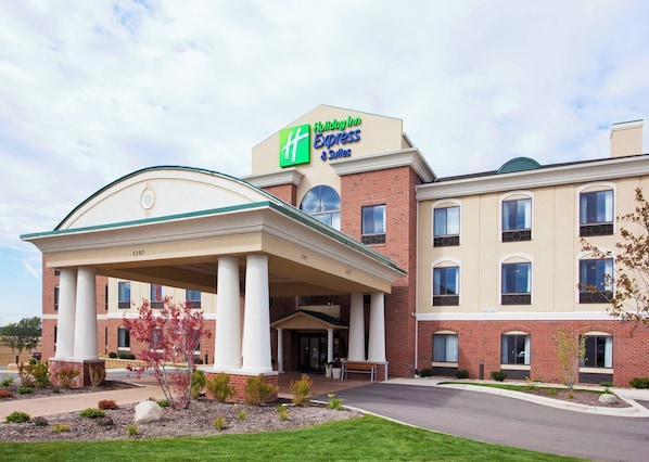 A Holiday Inn Express & Suites with a covered entrance, brick facade, and a clear sky.