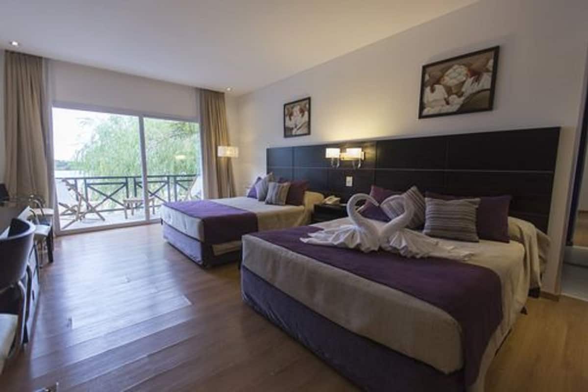 Ein Hotelzimmer mit zwei Betten, einem Balkon und einem Essbereich.