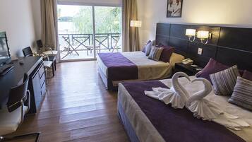 A hotel room with two beds, a desk with a computer, a balcony with a chair, and a TV.