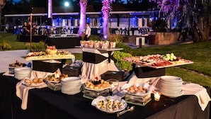An outdoor buffet setup with various food items and a band performing in the background. - Howard Johnson by Wyndham San Pedro Resort & Marina (San Pedro)