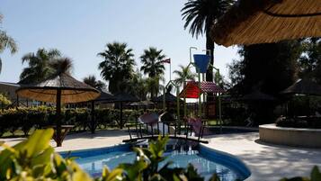 Relax by the resort pool surrounded by palm trees and comfortable lounge chairs.
