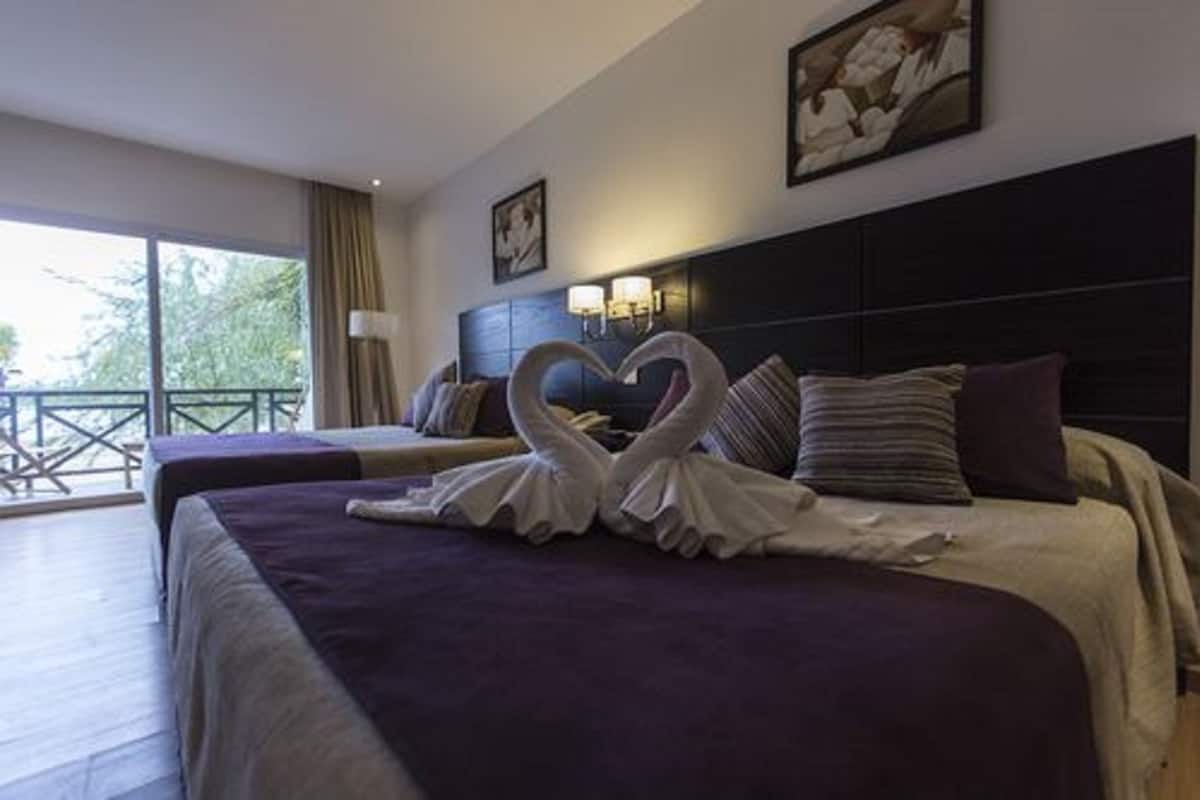 Ein Hotelzimmer mit zwei Betten und einem Balkon, dekoriert mit einem herzförmigen Handtuch.