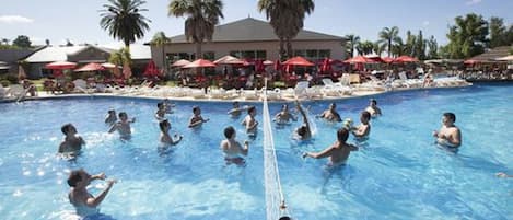 Una piscina techada, una piscina al aire libre, sombrillas