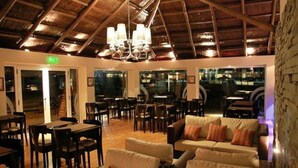 A restaurant with wooden ceiling beams, a chandelier, and a seating area with sofas and tables. - Howard Johnson by Wyndham San Pedro Resort & Marina (San Pedro)