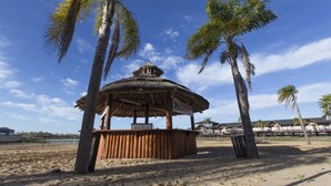 A beachside gazebo with a thatched roof, surrounded by palm trees and a sandy beach. - Howard Johnson by Wyndham San Pedro Resort & Marina (San Pedro)