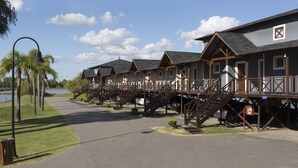 A row of wooden cabins with external staircases, a paved walkway, and a body of water in the background. - Howard Johnson by Wyndham San Pedro Resort & Marina (San Pedro)