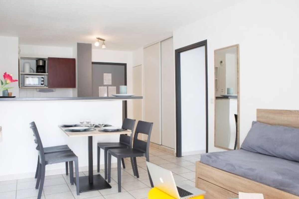 A modern living room with a sofa and a dining area with chairs and a table.