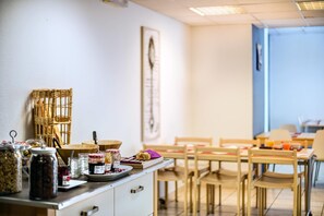 A breakfast buffet with various food items and a wicker basket. - Comfort Aparthotel Divonne La Versoix (Divonne-les-Bains)