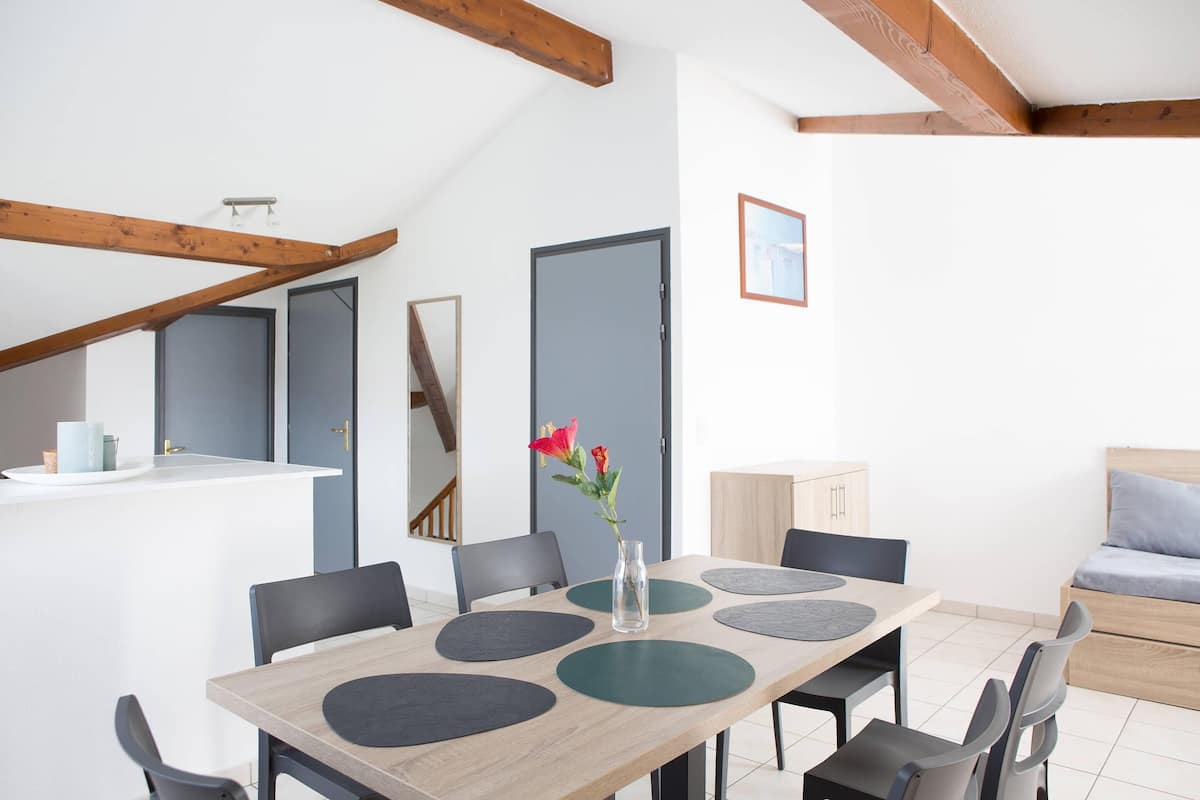 A modern dining area with a wooden table, black chairs, and a vase with flowers.