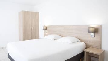 A modern bedroom with a large bed, two bedside tables, and a wardrobe.