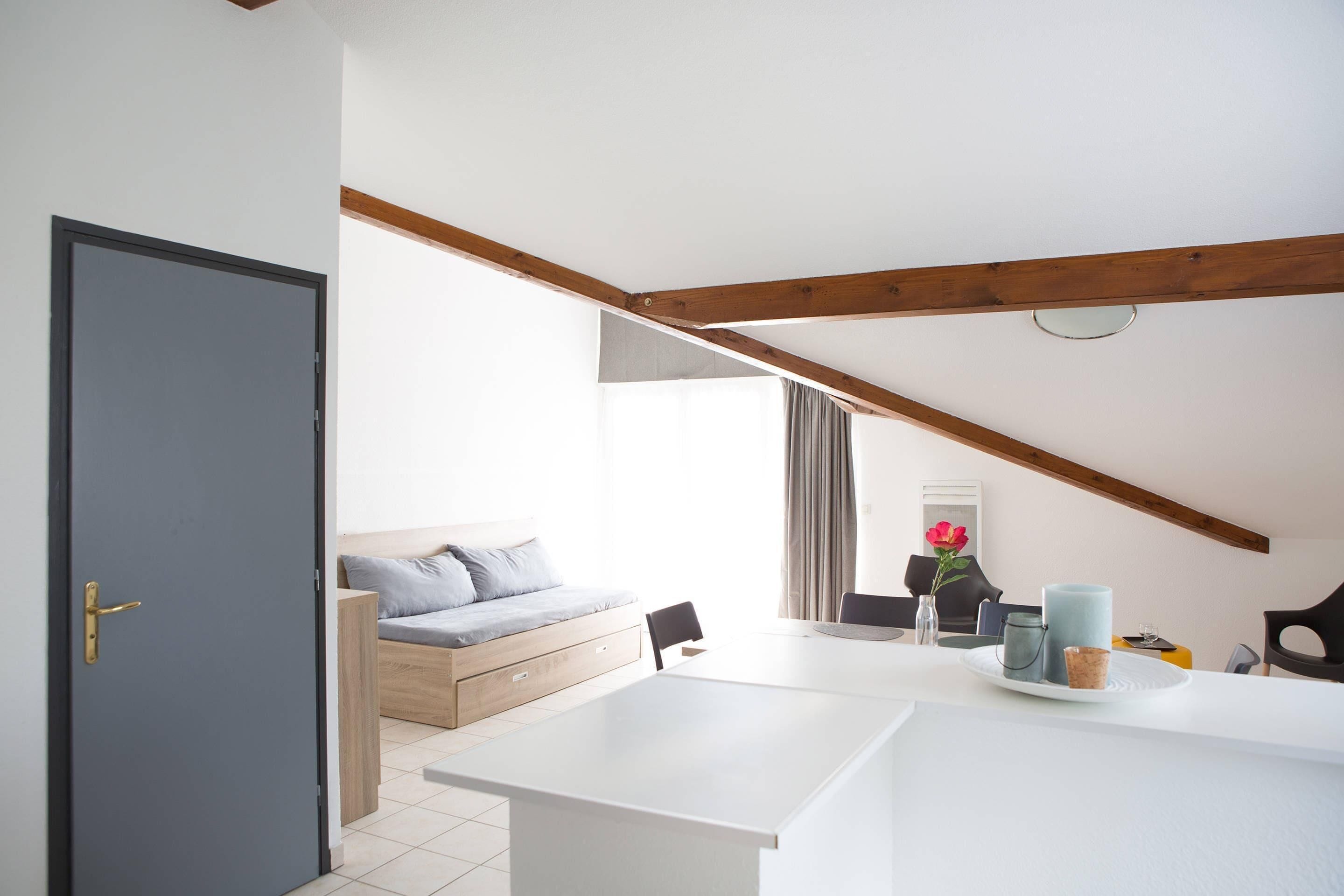 A modern room with a bed, a dining table, and a kitchen area.