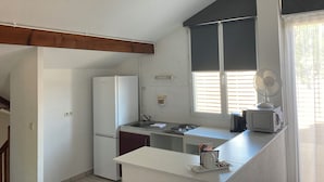 Una cocina compacta con refrigerador, lavamanos y microondas en la encimera.