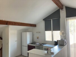 Uma cozinha compacta com geladeira, pia e micro-ondas na bancada.