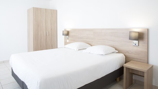 Un dormitorio moderno con una cama grande, dos mesitas de noche y un armario.