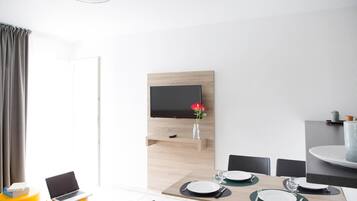 A modern dining area with a wooden table, chairs, and a television mounted on the wall.